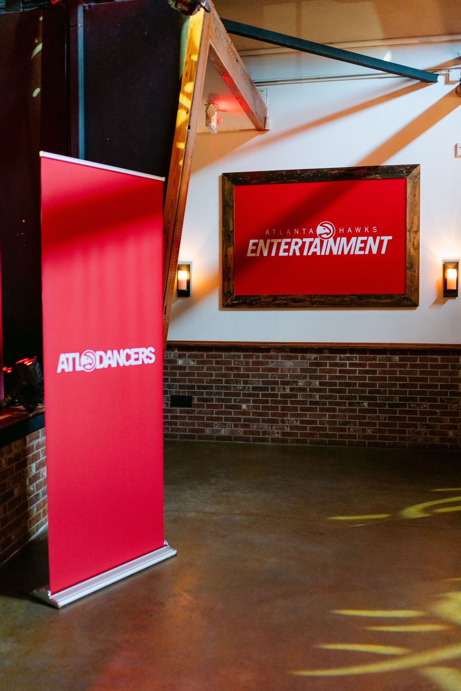 Atlanta Hawks Entertainment banner and ATL Dancers red retractable sign displayed in a brick-walled event venue.