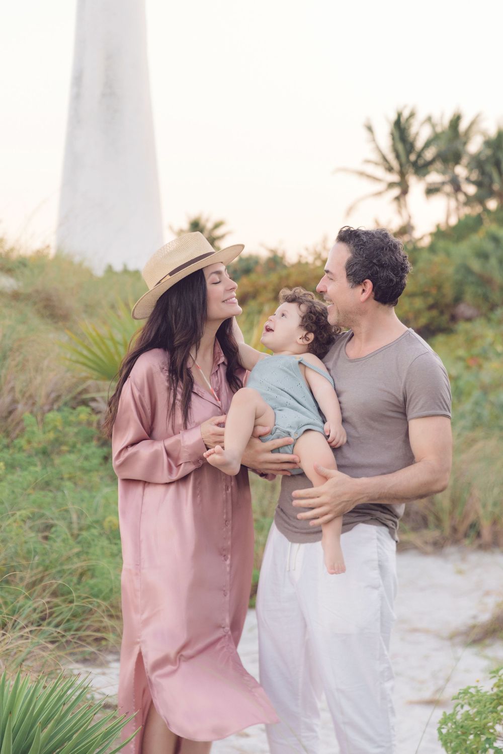 Family sharing joyful moment together near lighthouse at sunset.