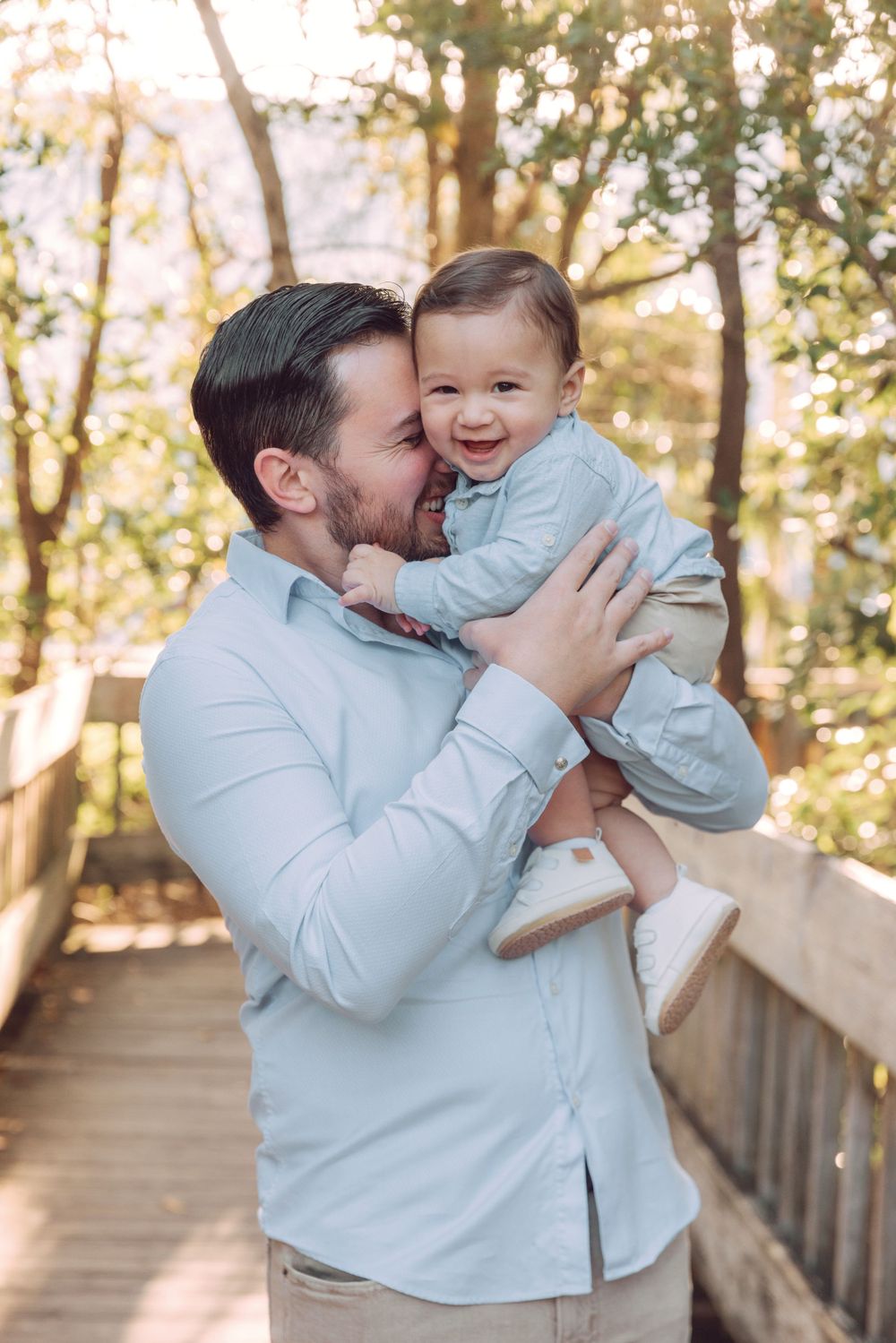 Joyful moment shared between parent and baby on wooden boardwalk in nature setting.