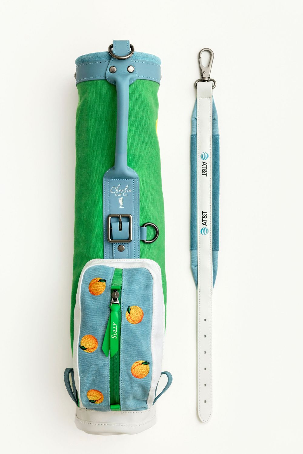 Green suede golf bag with orange fruit embroidery and matching AT&T branded white leather strap on white background.