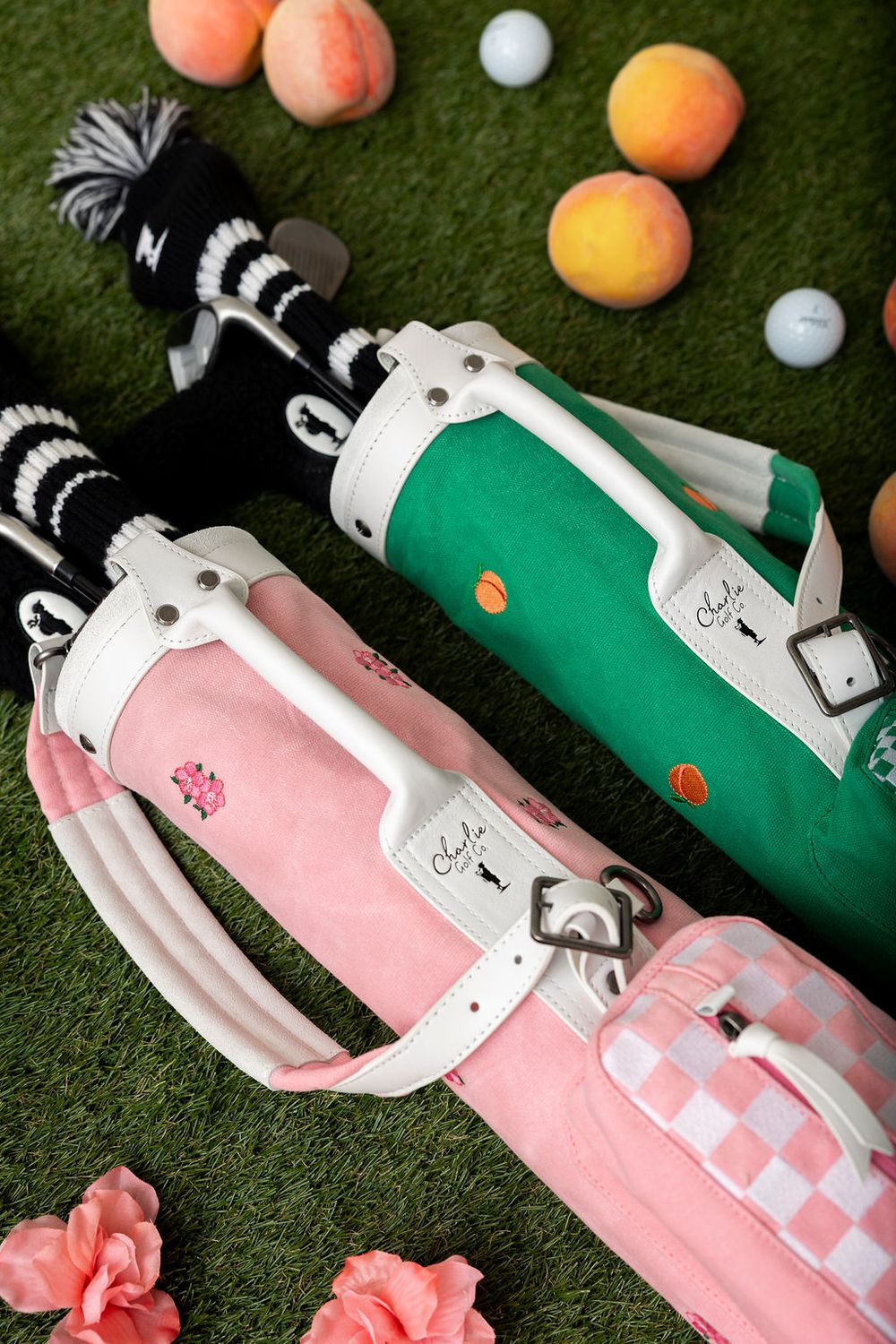 Golf ball and peaches arranged on green turf with pink and green golf club accessories.