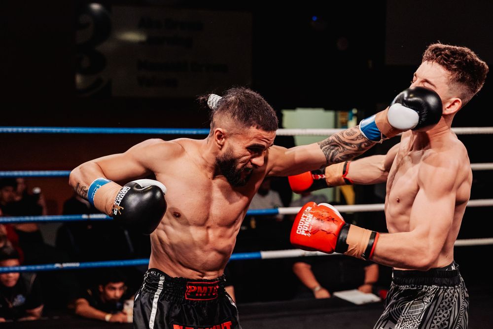 Two male boxers exchange punches in a professional boxing ring during an intense match.