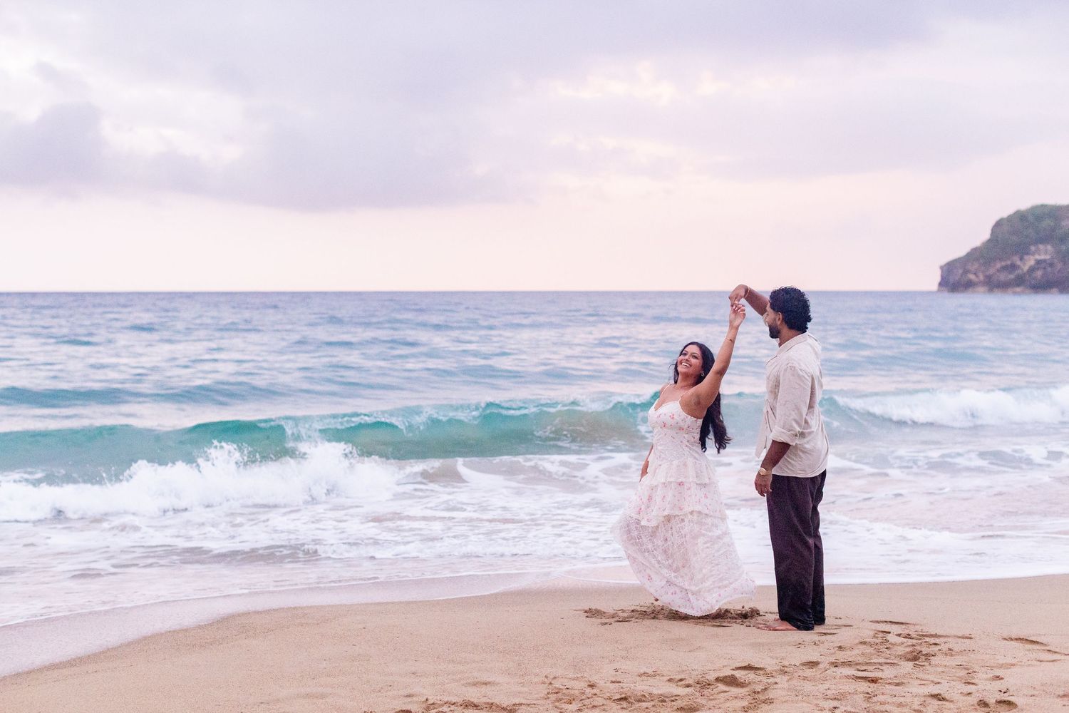 Engagement portrait on the beach. Man twirling woman at the water's edge. Playa Guajataca, Isabela, Puerto Rico.