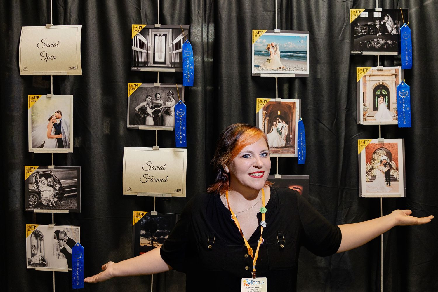 Woman proudly displays award-winning wedding photography prints at a professional photography competition booth.