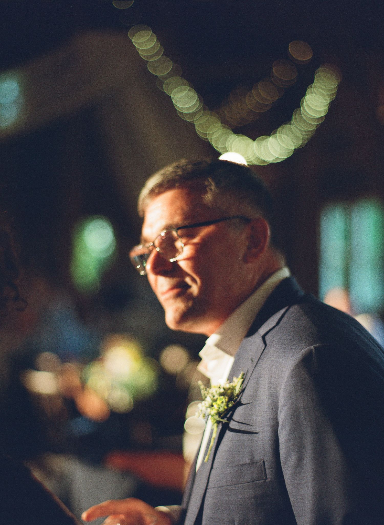 Smiling older man in gray suit with boutonniere at elegant wedding ceremony.