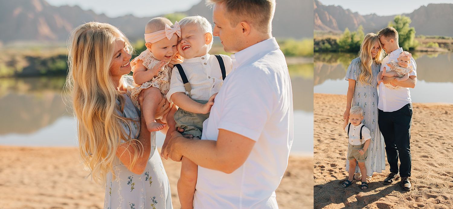 A happy young family with two babies poses on a sandy riverbank with mountains in the background.