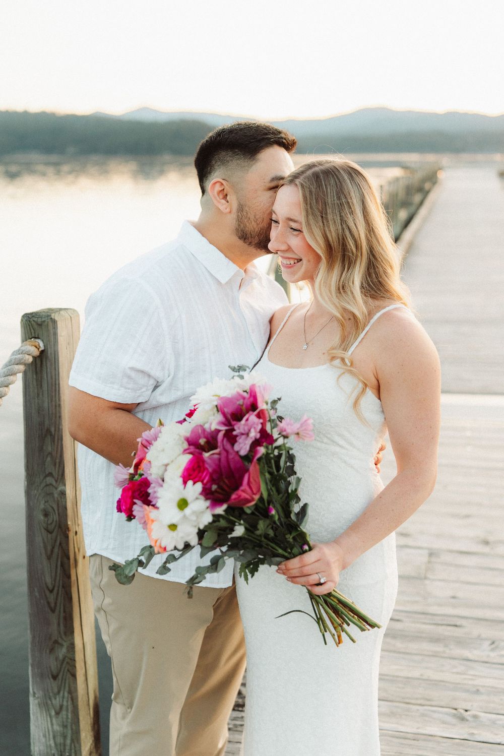 Couple on a dock at sunset, woman holding a colorful bouquet.