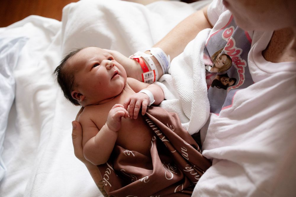 Newborn baby with dark hair wearing a hospital ID bracelet iduring a Fresh 48 session at Parkwest Medical Center.