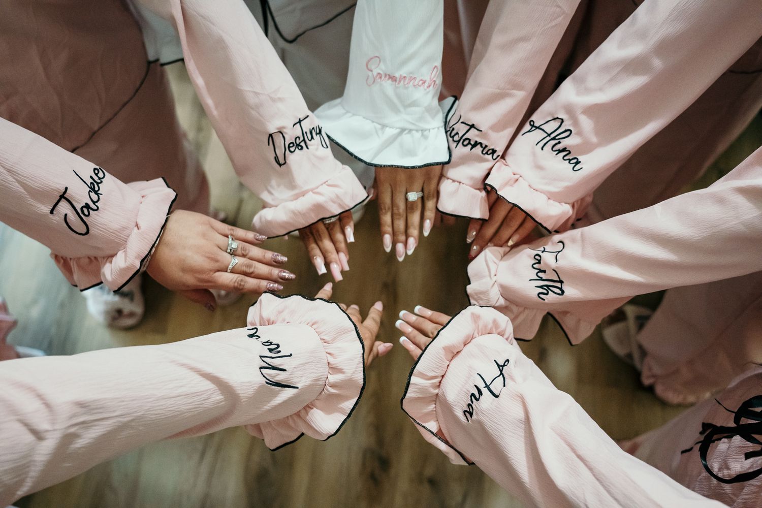 Bride in white satin robe with embroidered name touching her wedding dress before the ceremony.