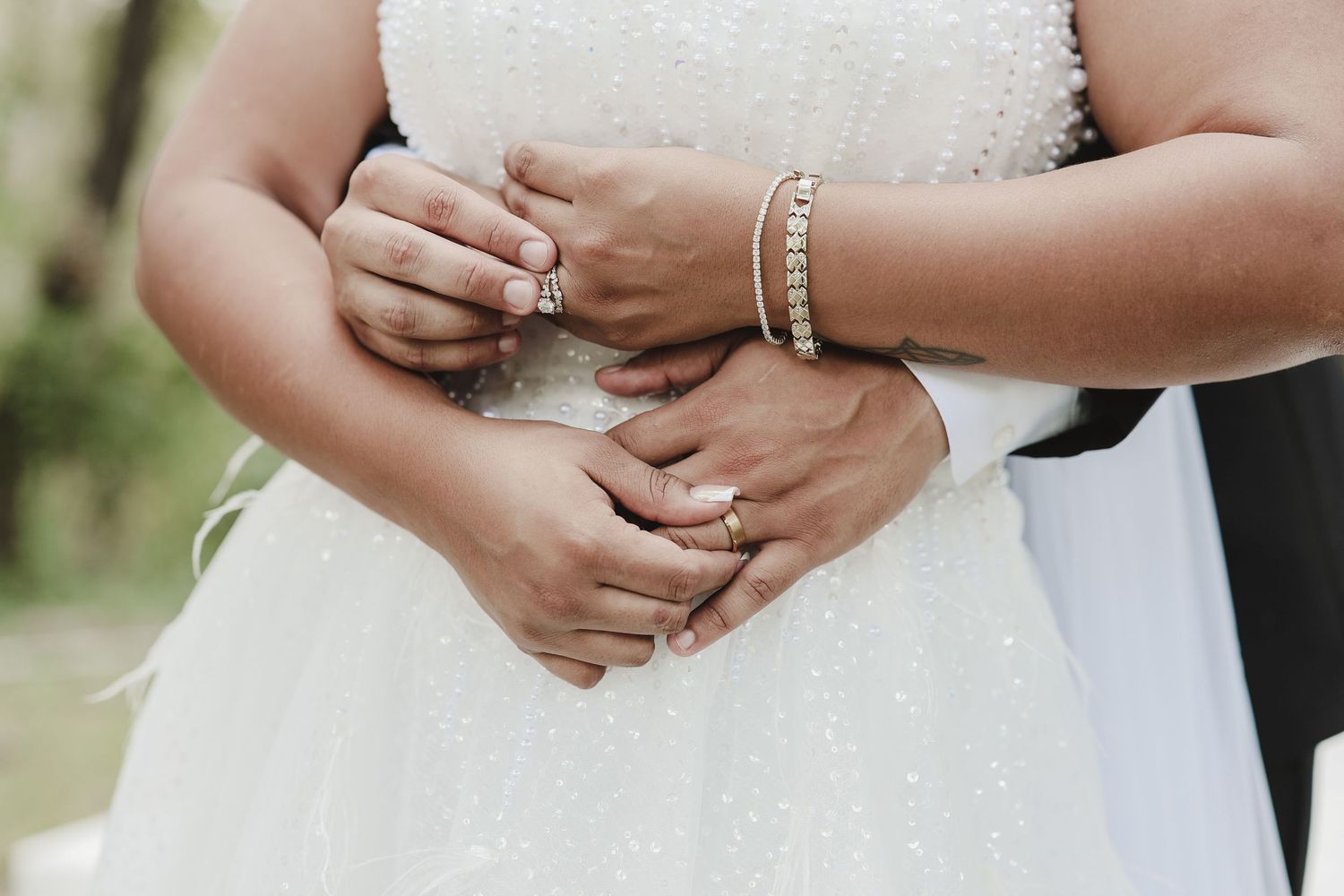 Close-up of bride and groom holding hands showing wedding rings and bridal details at The Starlight Garden.