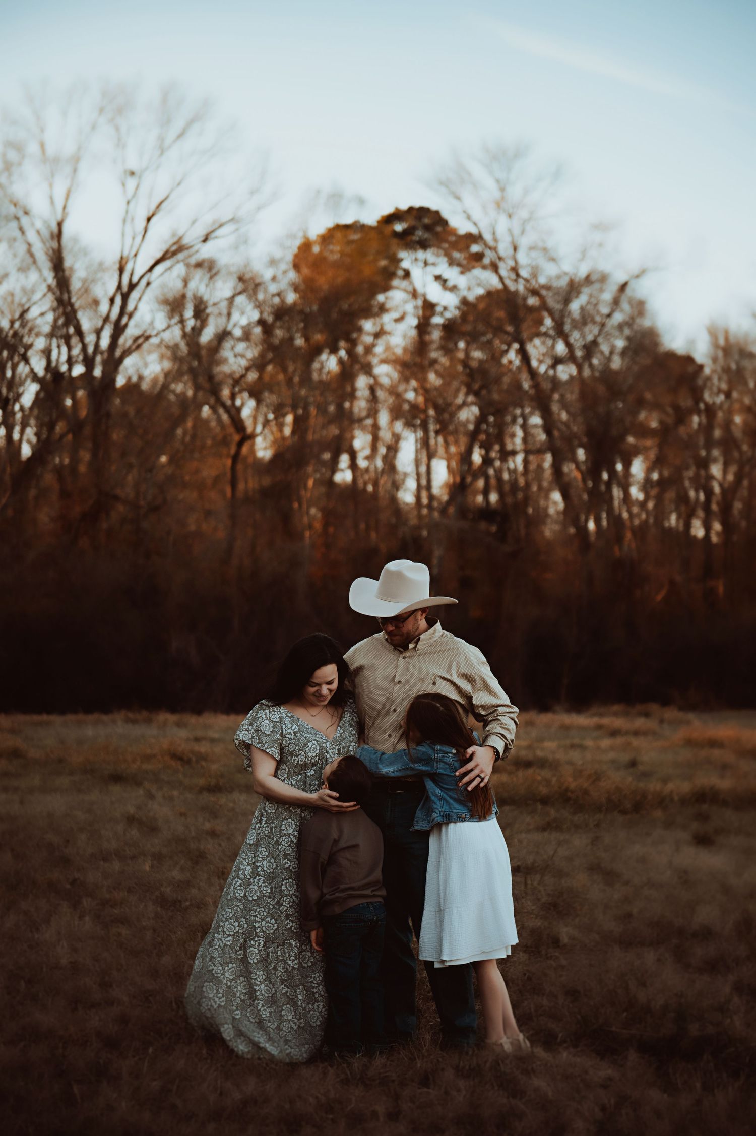 Best Family photographer in Nacogdoches. Image of the whole family cuddling in a field at sunset.