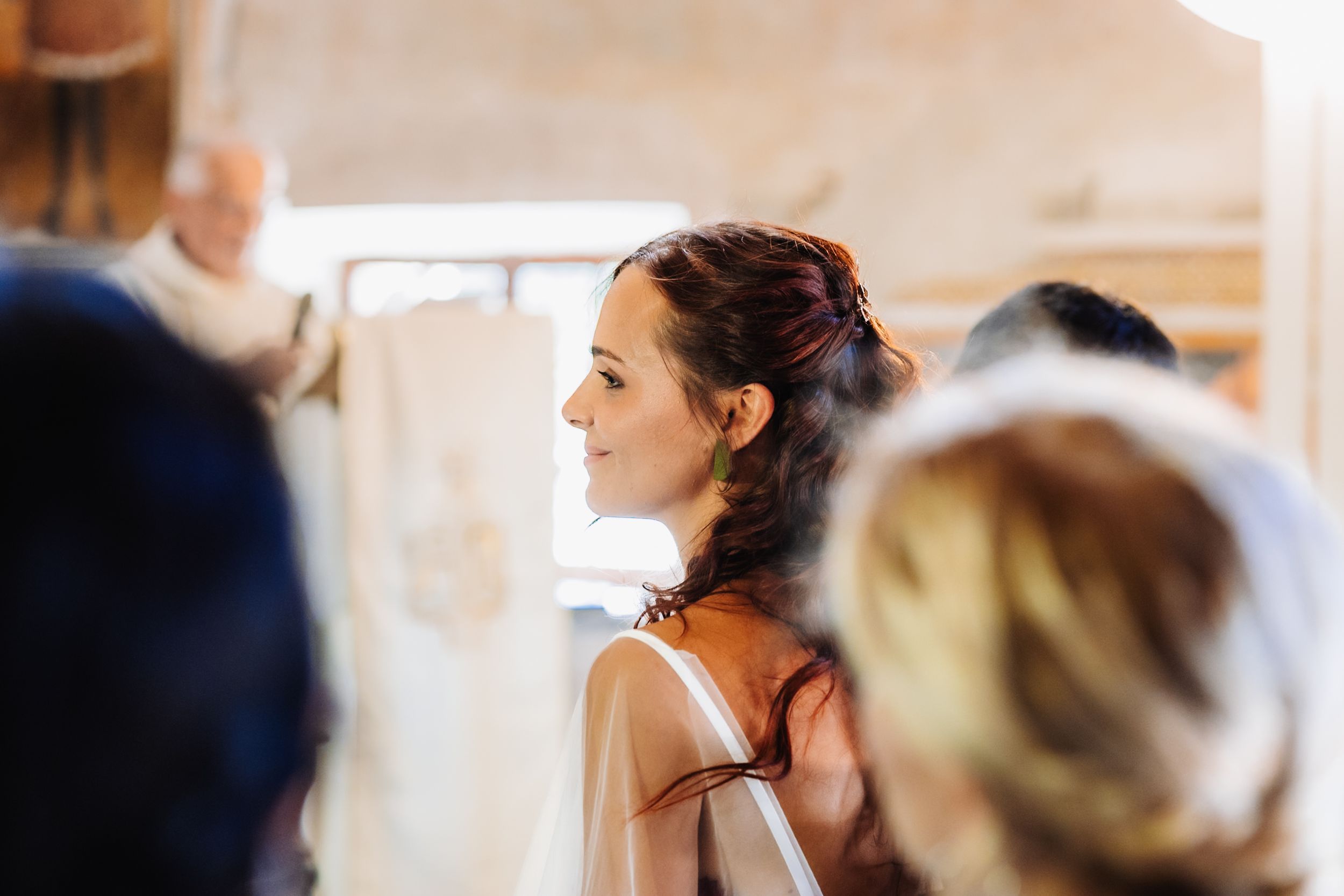 A bride gazes upward with a soft smile during her wedding ceremony preparations indoors.
