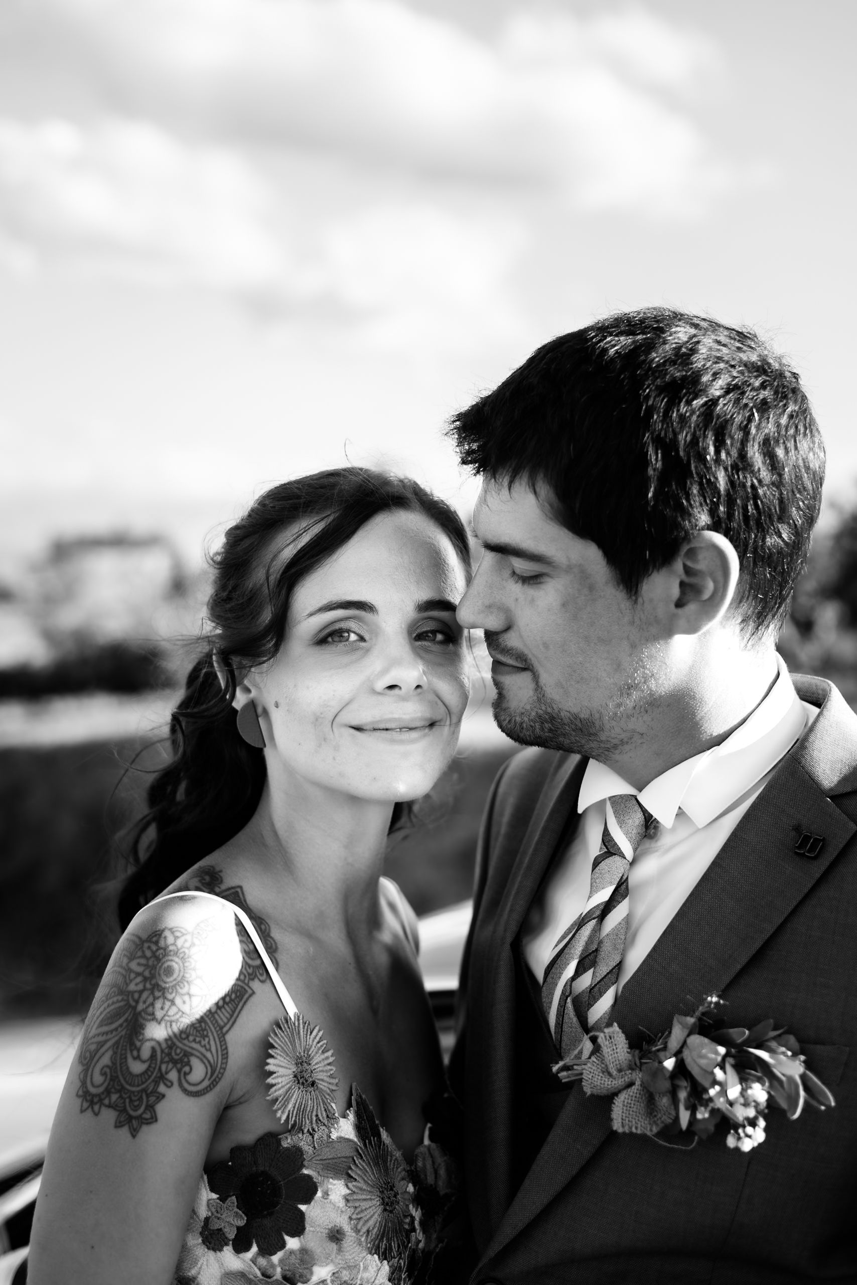 Black and white portrait of bride and groom sharing intimate moment outdoors on wedding day.