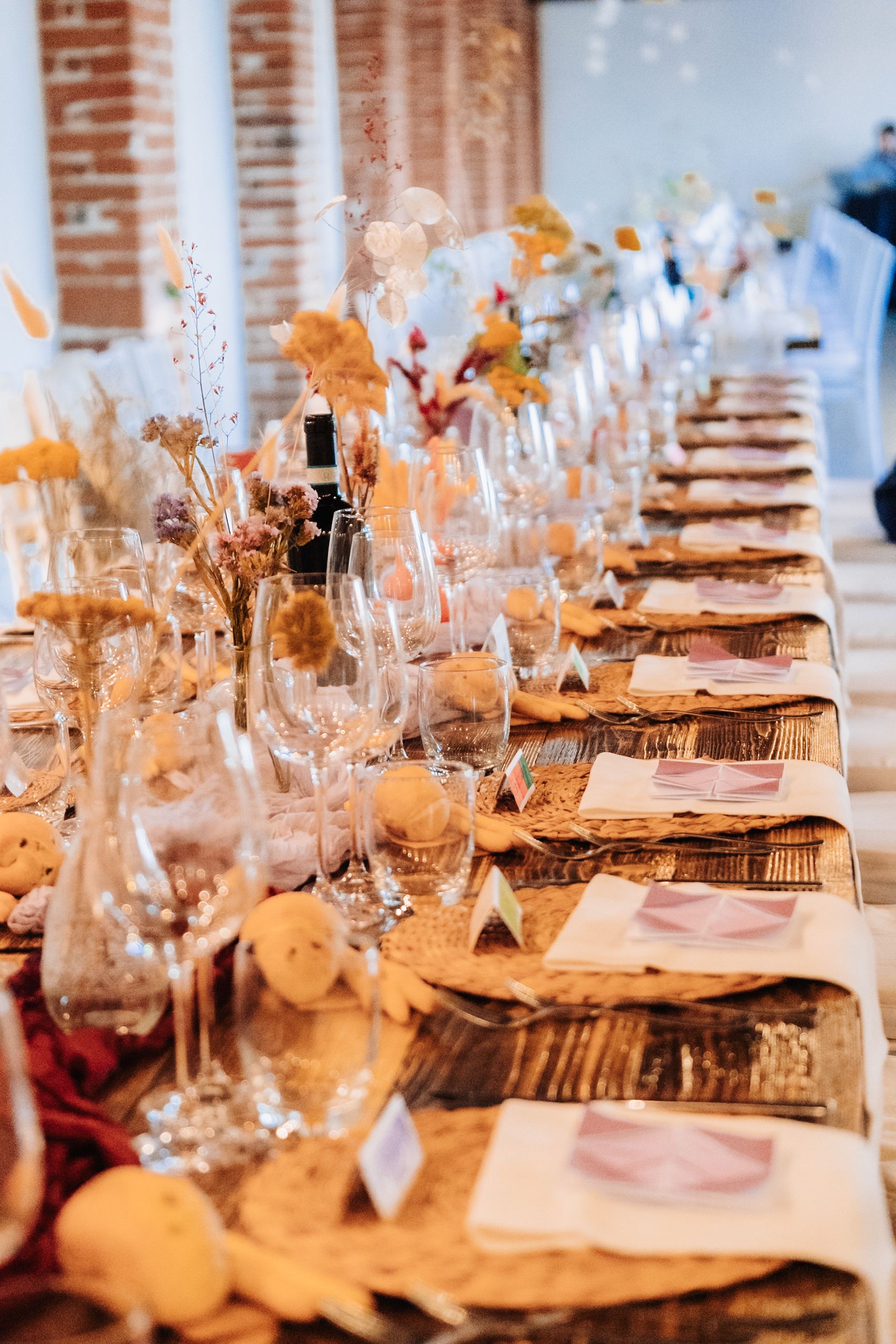Elegant rustic wedding reception table with autumn floral arrangements, wine glasses, and warm-toned place settings.