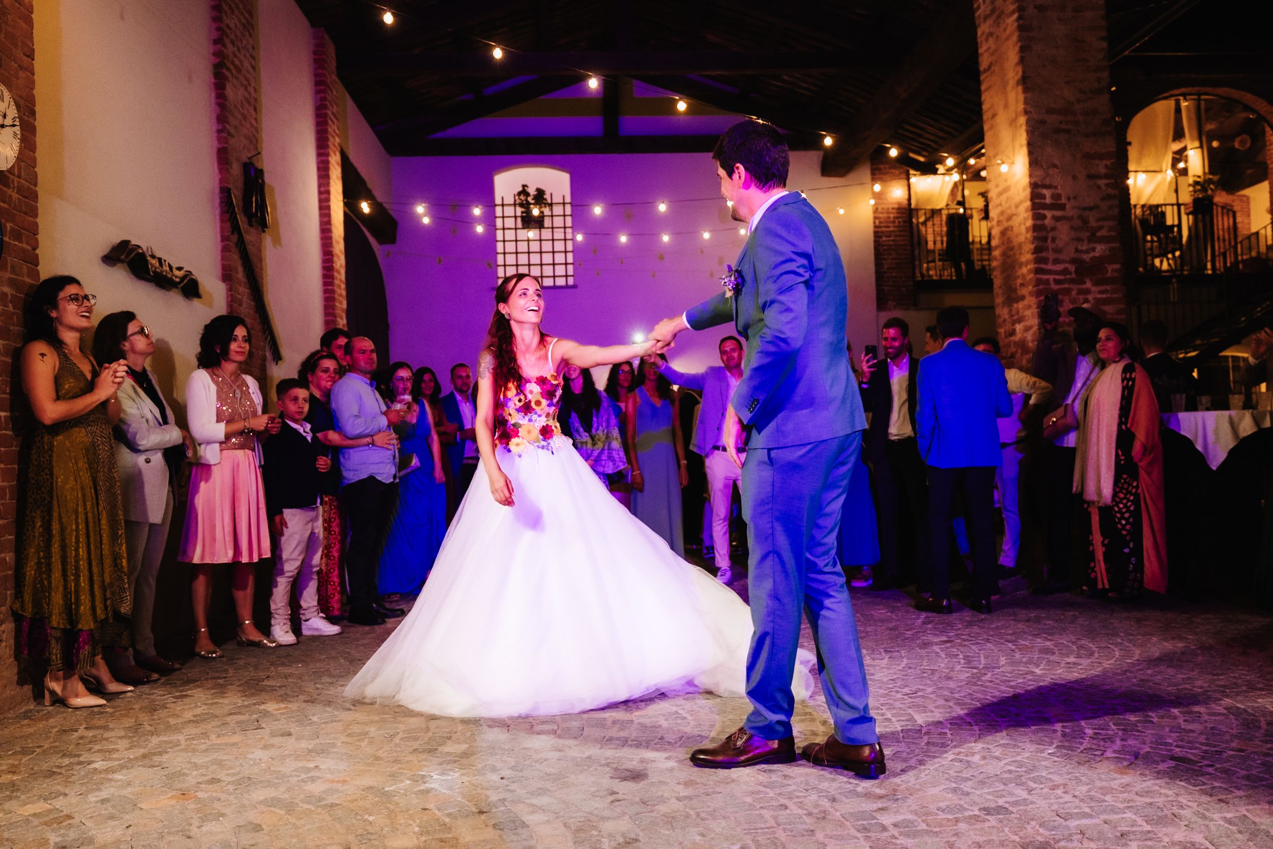 Bride and groom share their first dance surrounded by guests at a romantic wedding reception.
