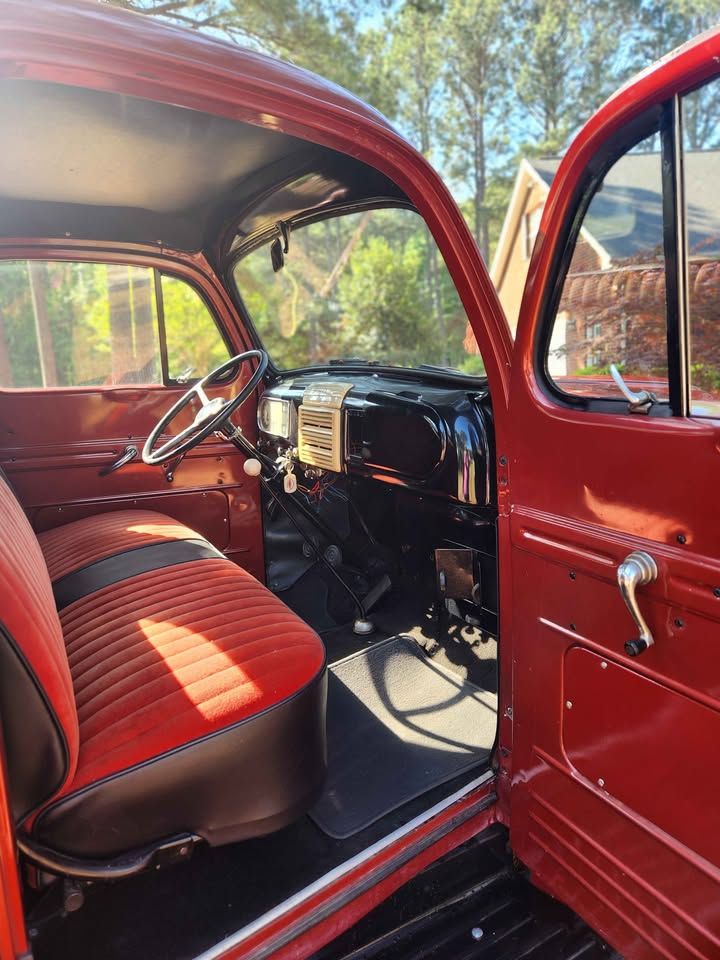 Restored classic red truck interior featuring red and black bench seat, vintage steering wheel, and chrome dashboard details.