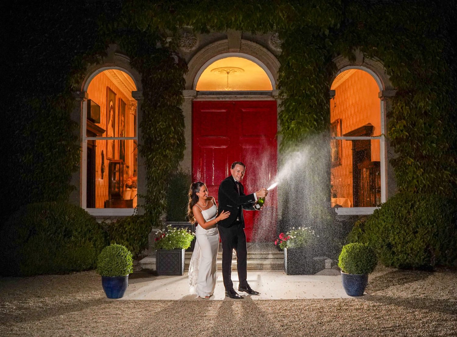 Romantic couple silhouetted in a glowing Gothic arch doorway surrounded by atmospheric mist at night.