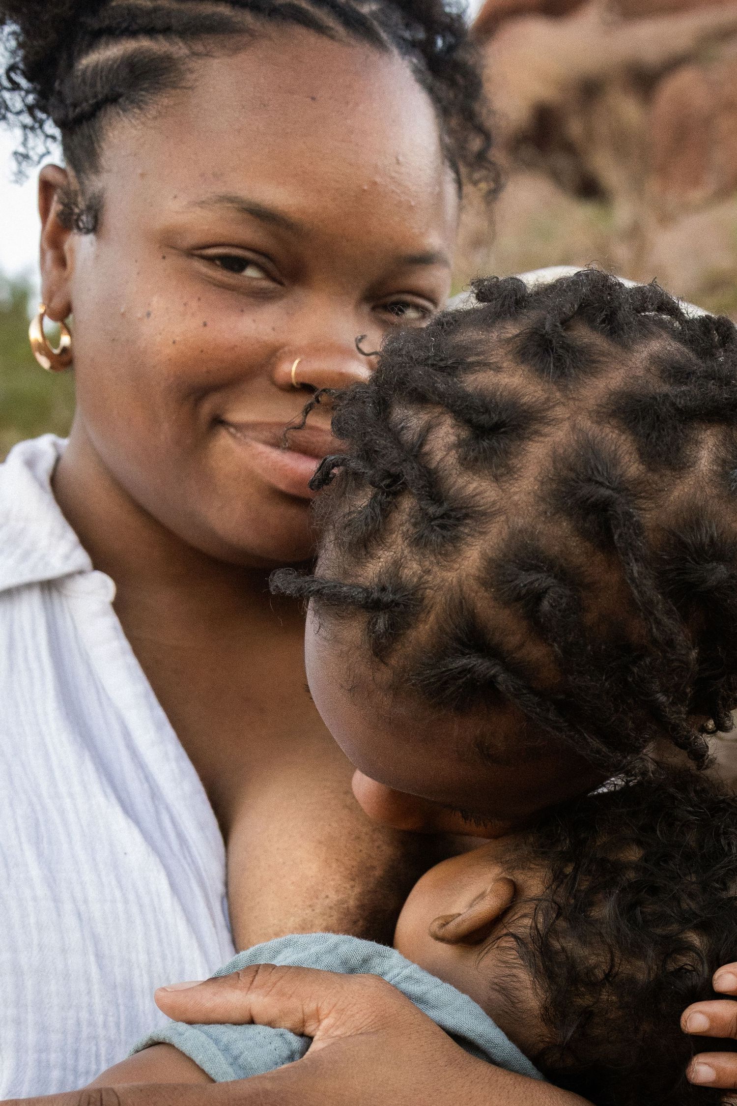A smiling Black mother breastfeeds her baby outdoors in natural setting at Papago Park in Phoenix.