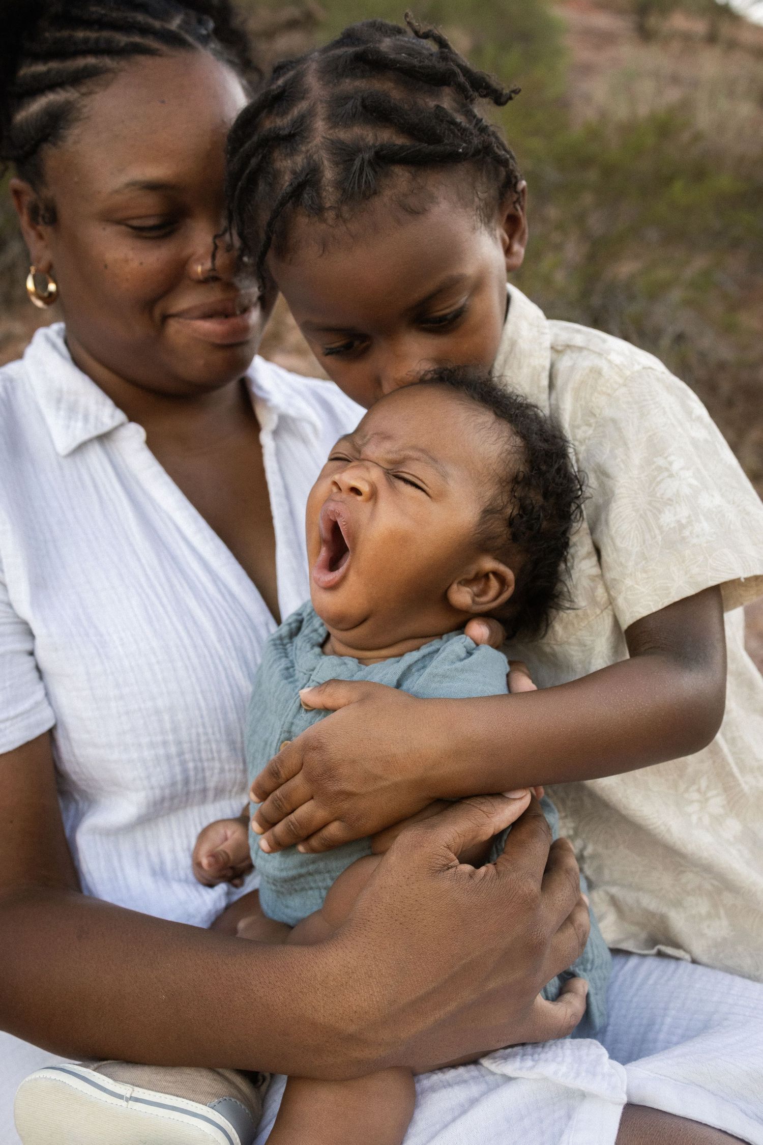 A mother and older child share a tender moment with a yawning baby at Papago Park in Phoenix.