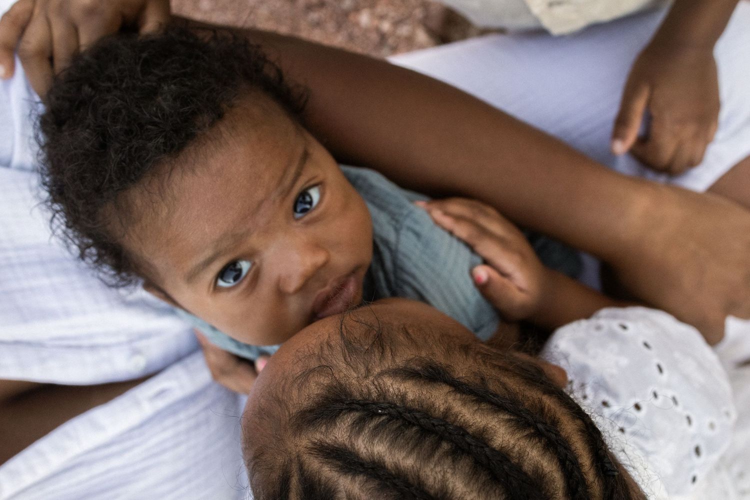 A Black mother breastfeeding her newborn baby while lying down, with the infant gazing upward at Papago Park in Phoenix.