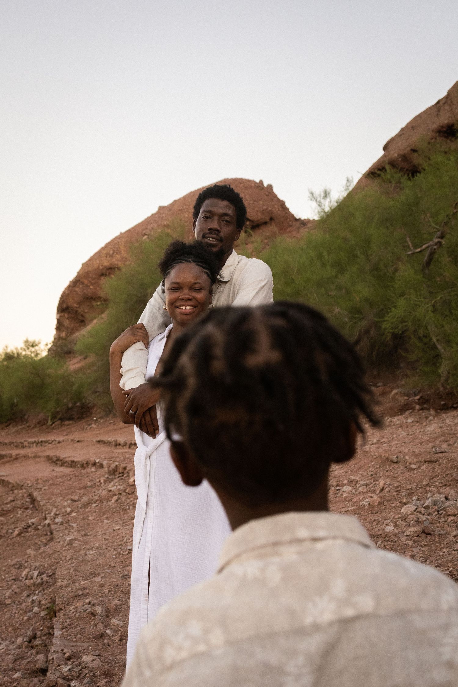 A happy Black couple embraces outdoors near red rock formations at dusk at Papago Park in Phoenix.