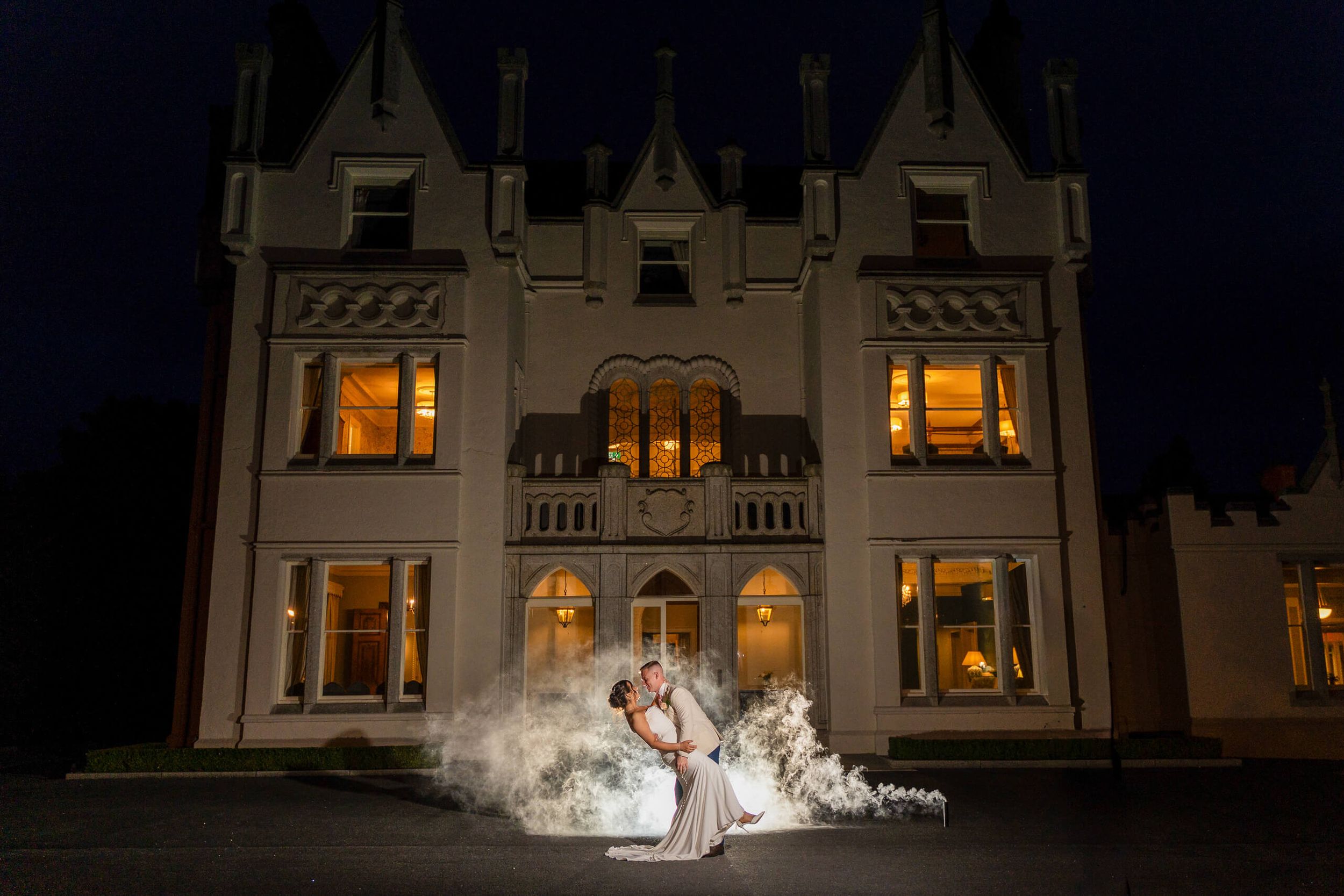 Bride and groom embrace in a dramatic dip beneath a glowing Ballykealey house county Carlow photo by AK wedding photography and videography.