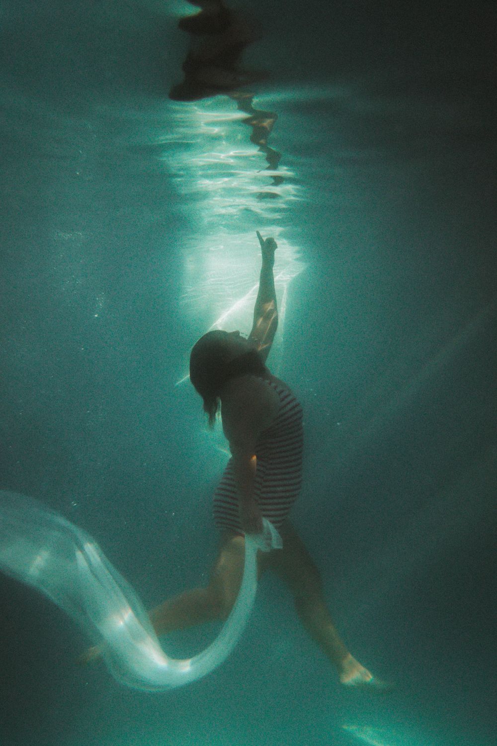 portrait of a woman looking up to the surface to touch her reflection in a pool underwater photography workshop NSW