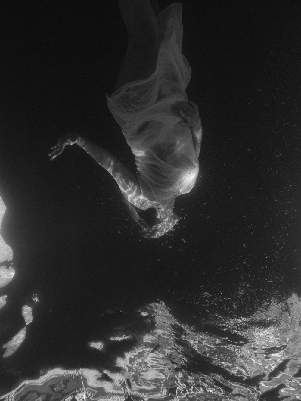 abstract black and white portrait of a woman about to resurface from underwater on a pool session at Lake Macquarie, NSW