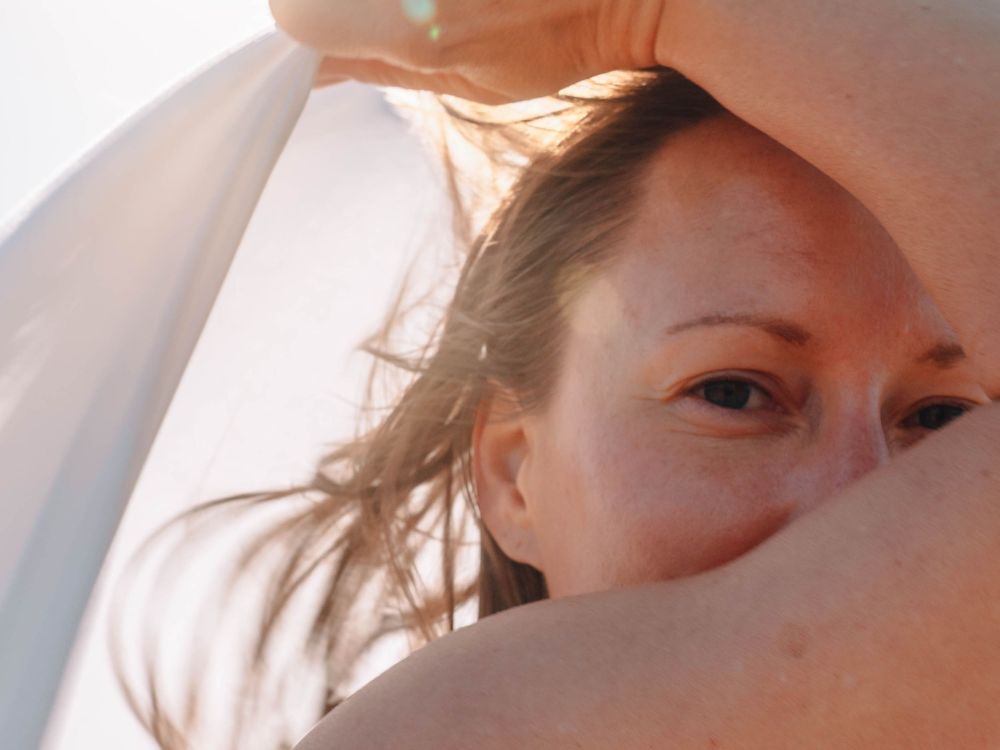woman smiling into the lens in backlist warm morning light on an empowerment portrait session The Tide of Her in Lake Macquarie NSW