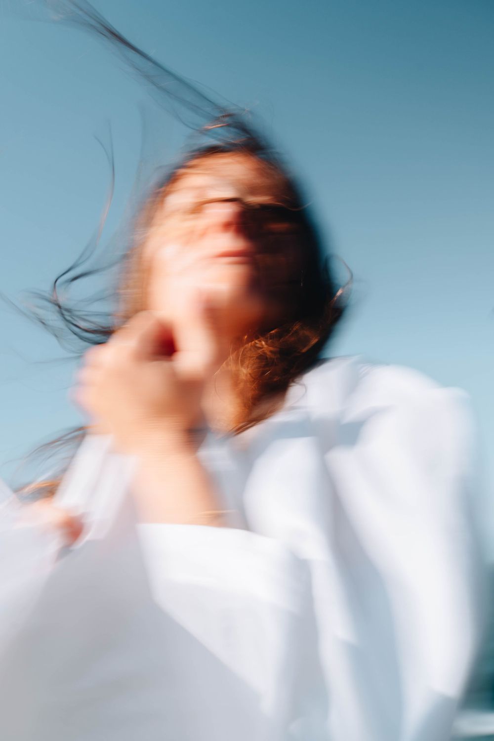 woman with wild hair in the wind facing the camera in blurry abstract long exposure portrait along coastal NSW