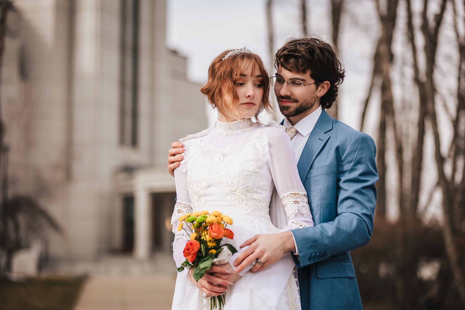 Groom wraps his arm around bride's shoulder during their elopement at Boston Massachusetts Temple in Belmont, MA, bride holding her bouquet