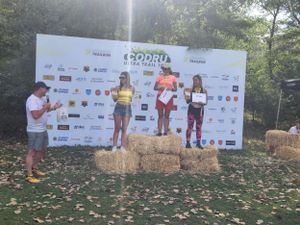 Female athletes on podium receiving awards at Codru Ultra Trail race awards ceremony outdoors.