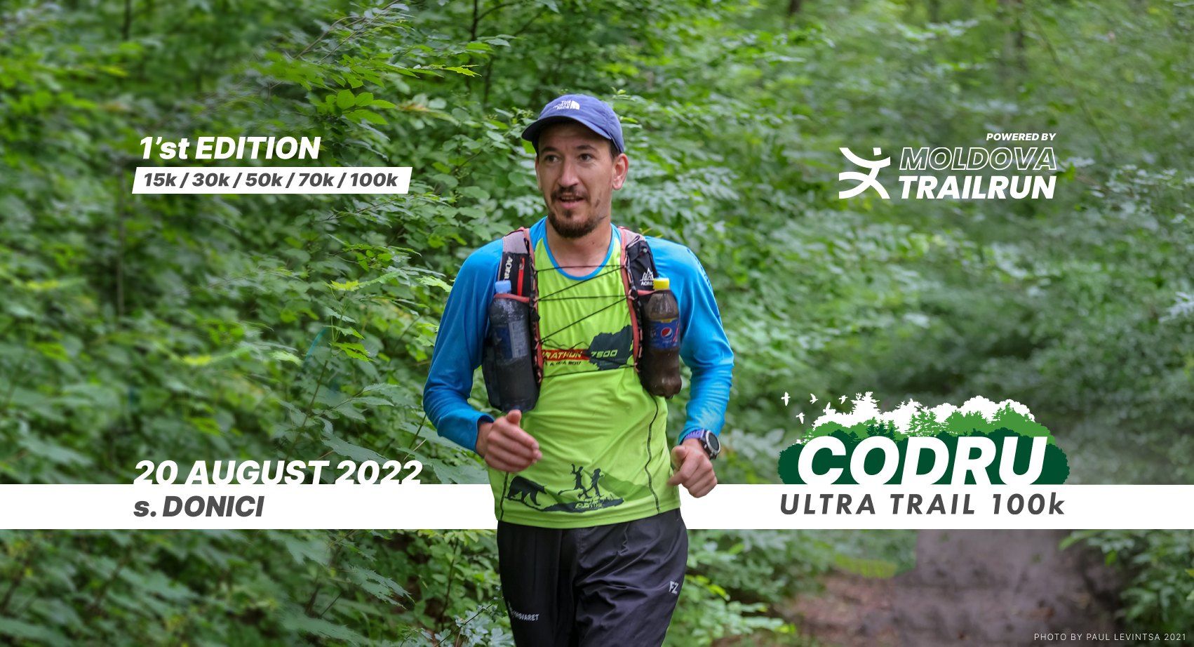 Trail runner competing in the 1st Edition Codru Ultra Trail 100k race through a lush green forest.
