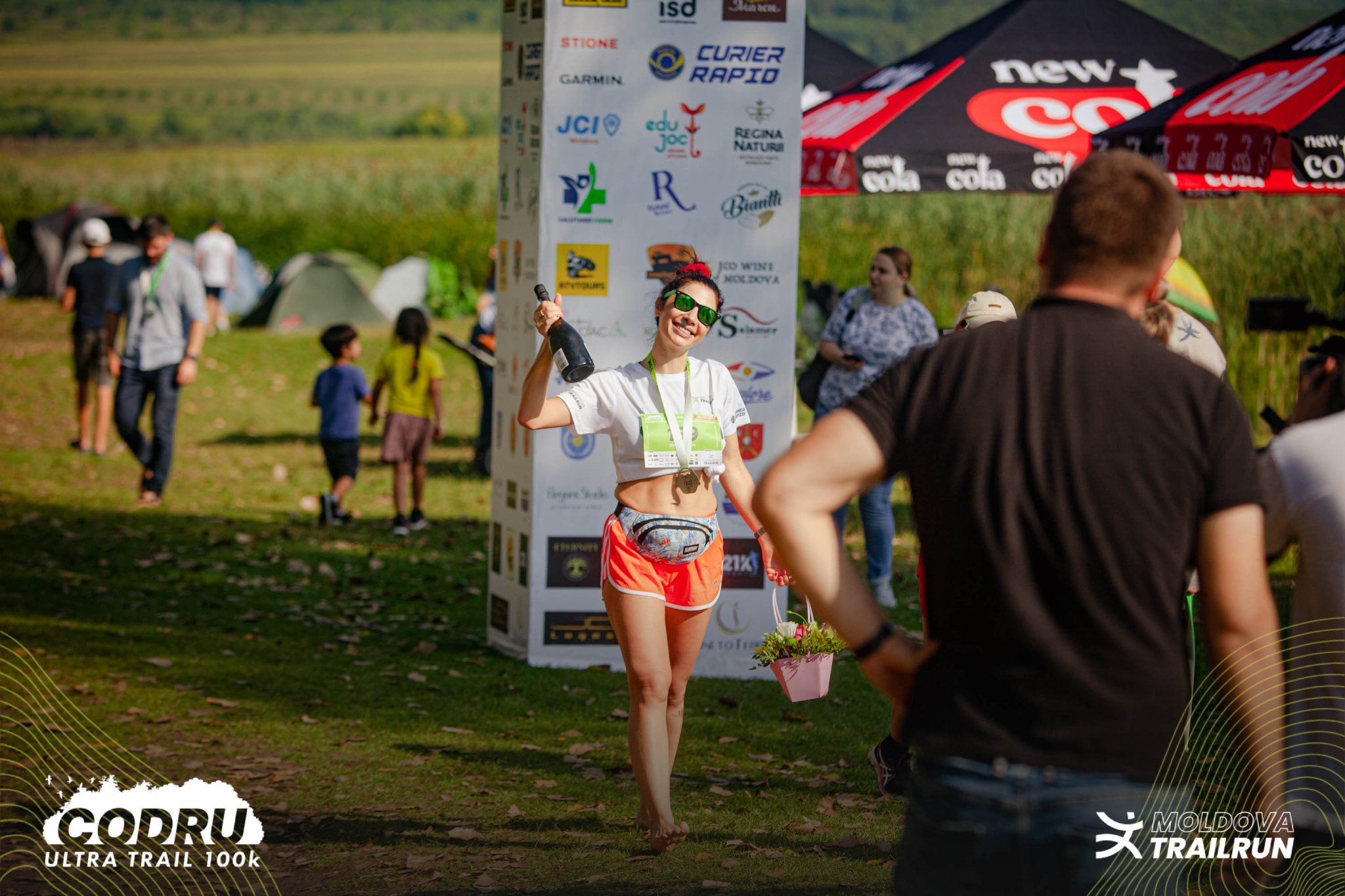 Female trail runner flexing at Codru Ultra Trail 100k race event with sponsors backdrop visible.