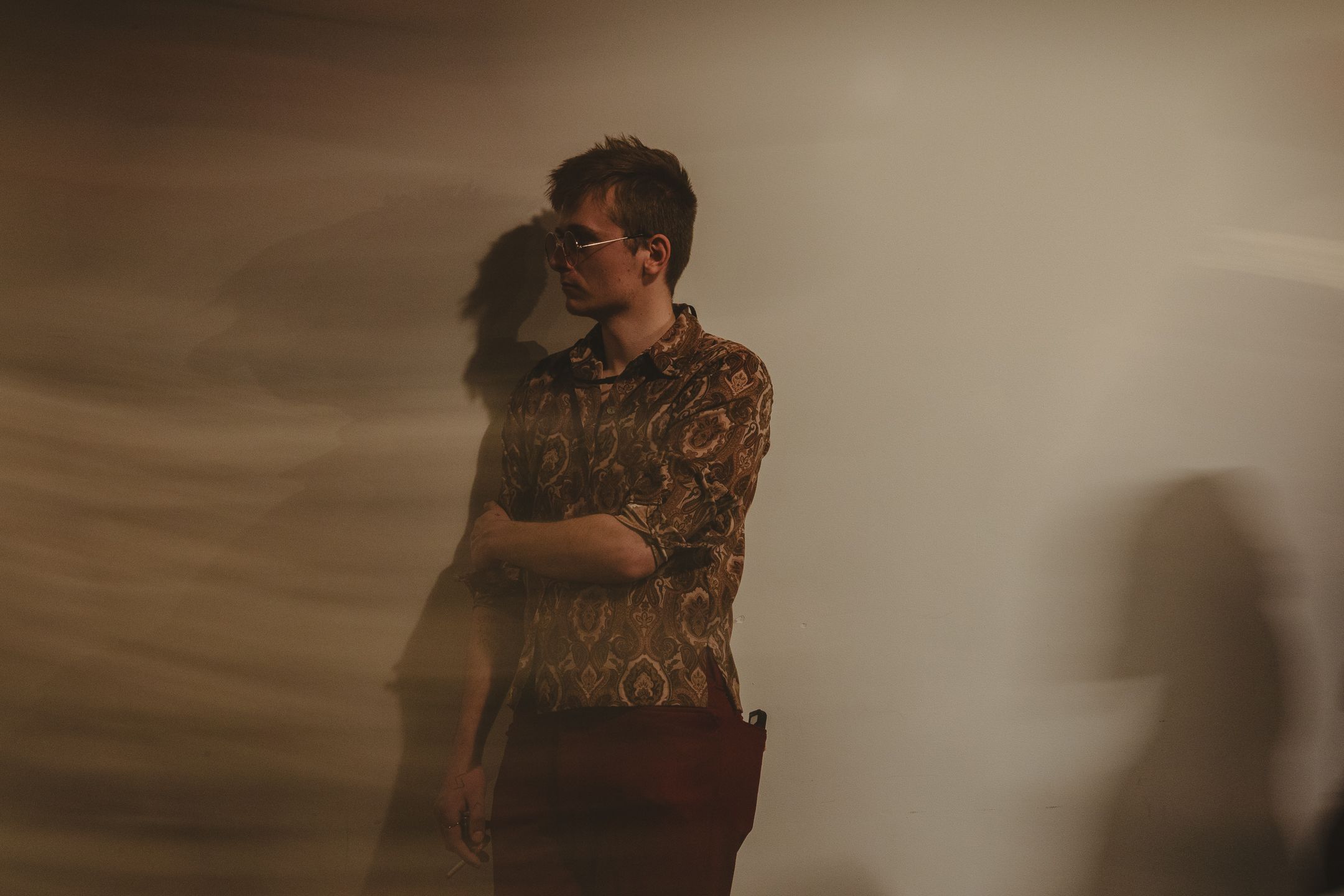 A person in a floral shirt embraces another in a dreamy, soft-lit atmospheric setting with warm golden tones.