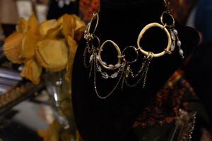 Gold hoop necklace with draped chains and crystal accents displayed on a black velvet jewelry bust.