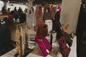 Colorful handmade crochet handbags displayed on a table at an indoor craft market.