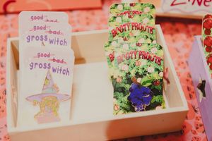 Handmade witch-themed bookmarks and Booty Fruits cards displayed in white wooden box at craft fair.