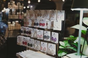 Colorful earrings displayed on a black retail stand in a boutique shop.
