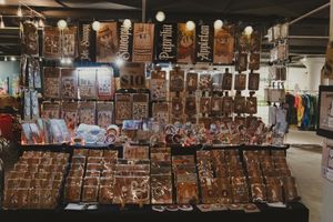A vendor booth filled with rows of dark wooden crafts, figurines, and hanging decorative items at an indoor market fair.