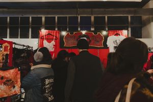 Crowd browsing colorful graphic t-shirts at an indoor vendor market booth.