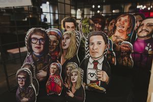 Handcrafted illustrated paper doll cutouts of various people displayed at an art market.