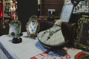 Vintage jewelry display with ornate frames and a decorative shoe holder showcasing necklaces on a white table.