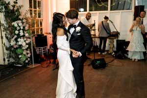 Bride and groom share their first dance kiss at elegant wedding reception with live band performing in background.