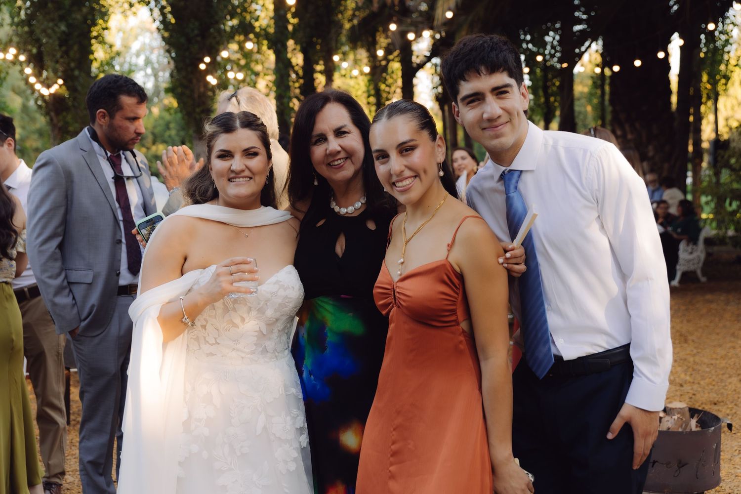 Bride and three wedding guests smiling together for a photo at a beautiful outdoor garden reception.