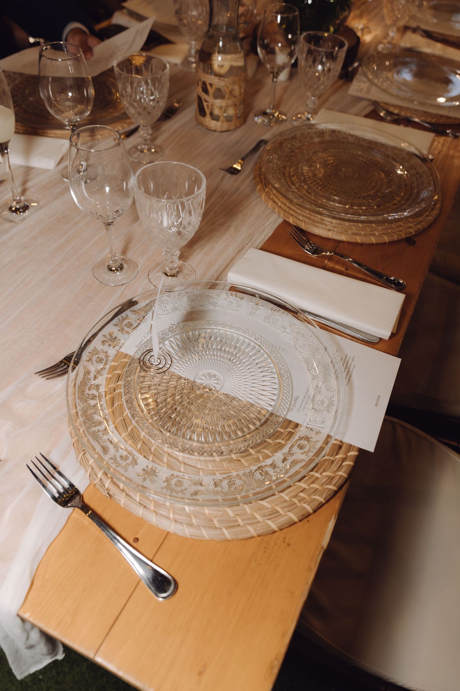 Elegant wedding table setting with crystal glassware, decorative charger plates, and white linen napkins.