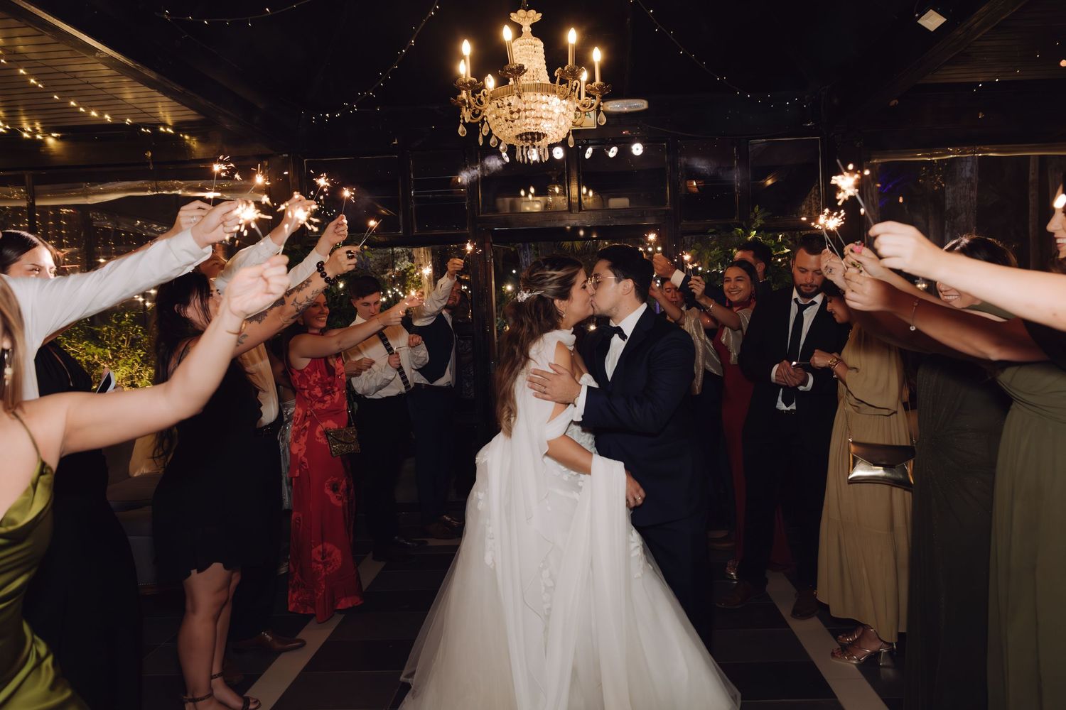 Bride and groom share a romantic kiss during a sparkler send-off exit at their elegant wedding reception.