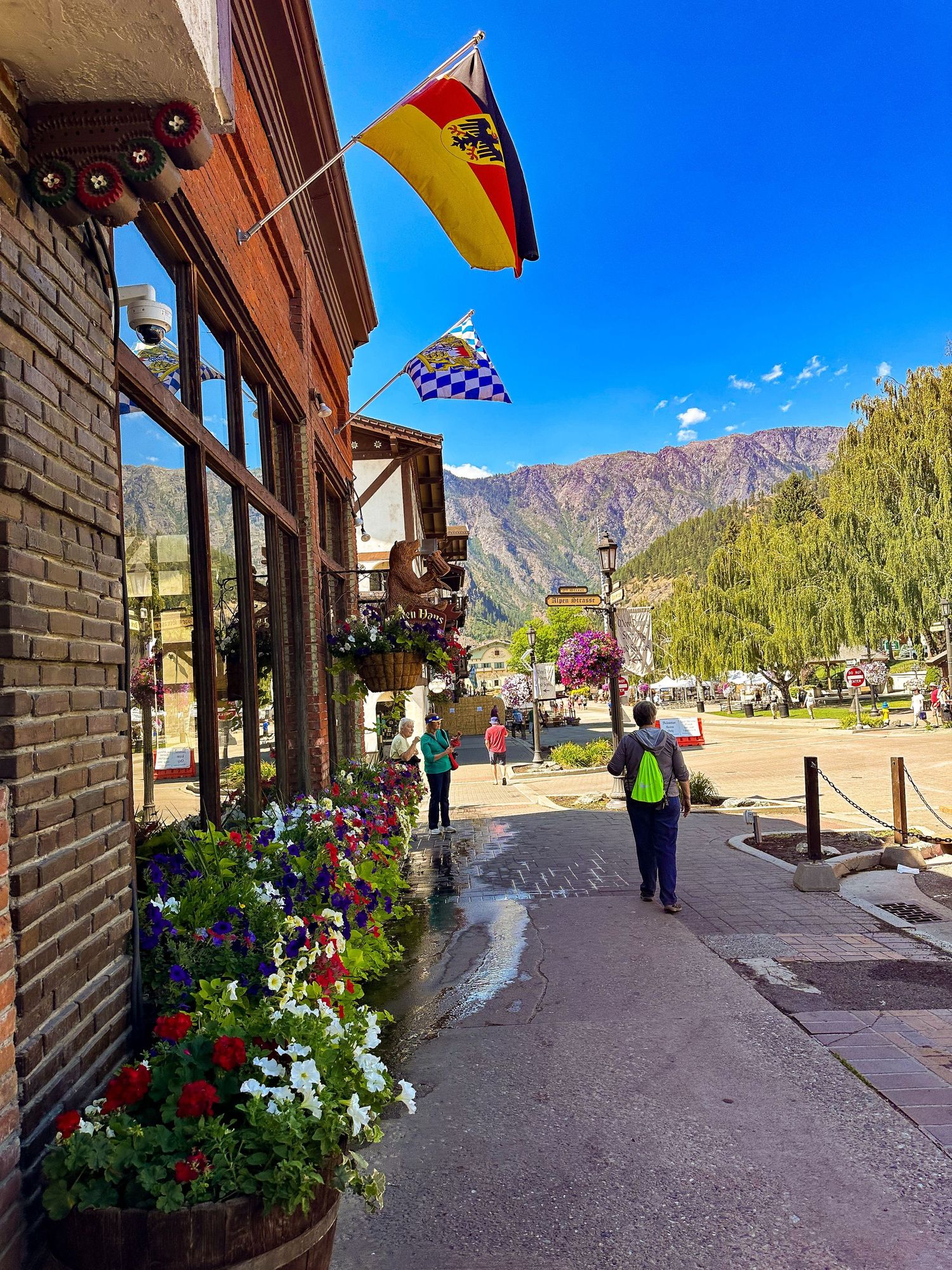 Charming mountain town street with colorful flowers and European-style flags.