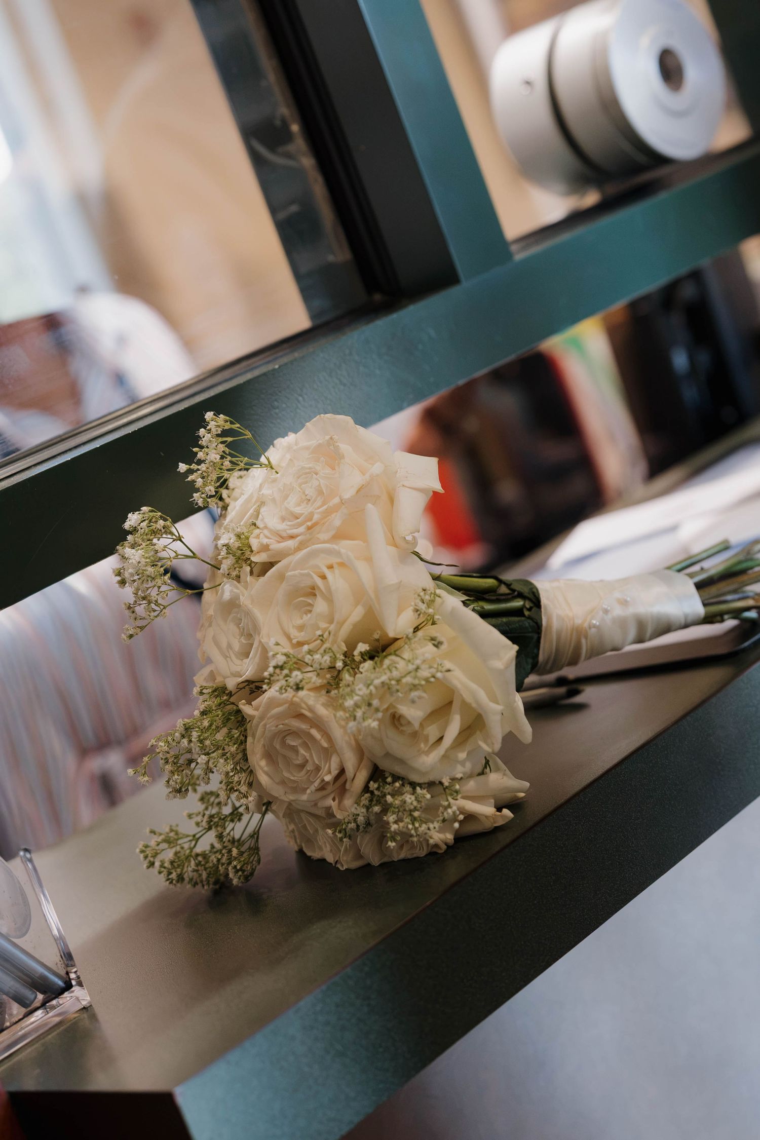 White rose wedding bouquet with baby's breath resting on a shelf.