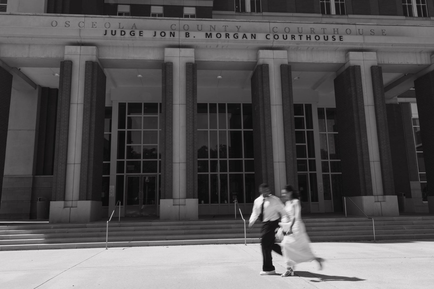 Couple shares romantic moment outside Judge Jon B. Morgan Courthouse in black and white wedding photo.